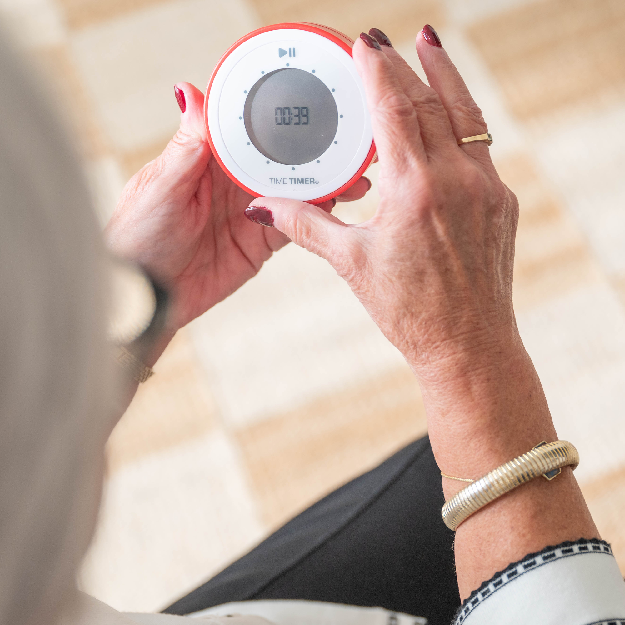 The 90-minute TWIST® Timer in Original Red being held by an elderly woman