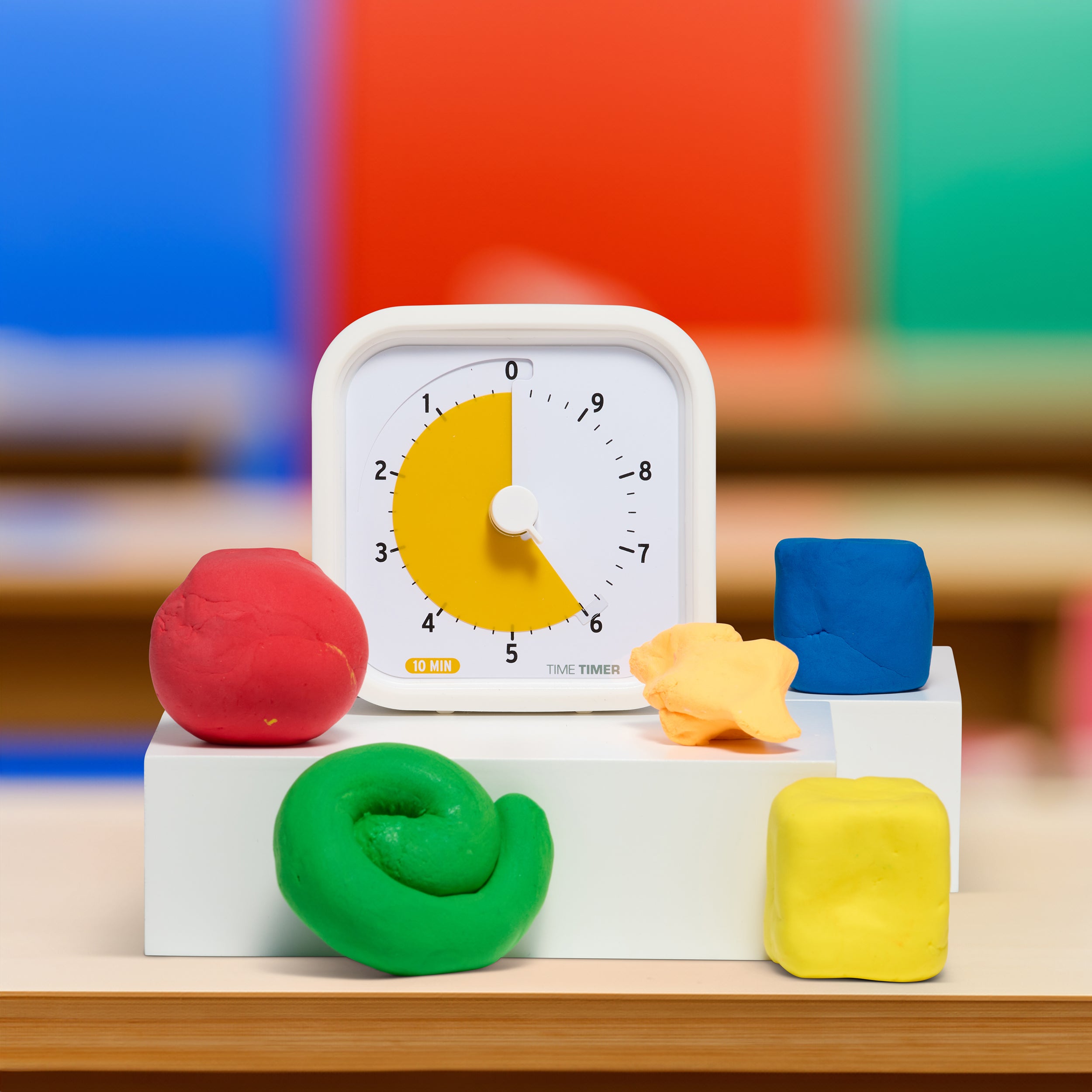 The Time Timer MOD Education Edition 10 Minute timer is shown next to some play dough shapes in colorful classroom setting. 