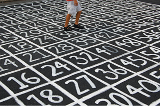 Man walking on pavement with chalk boxes of numbers