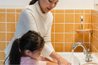 Mom teaching her daughter how to wash her hands
